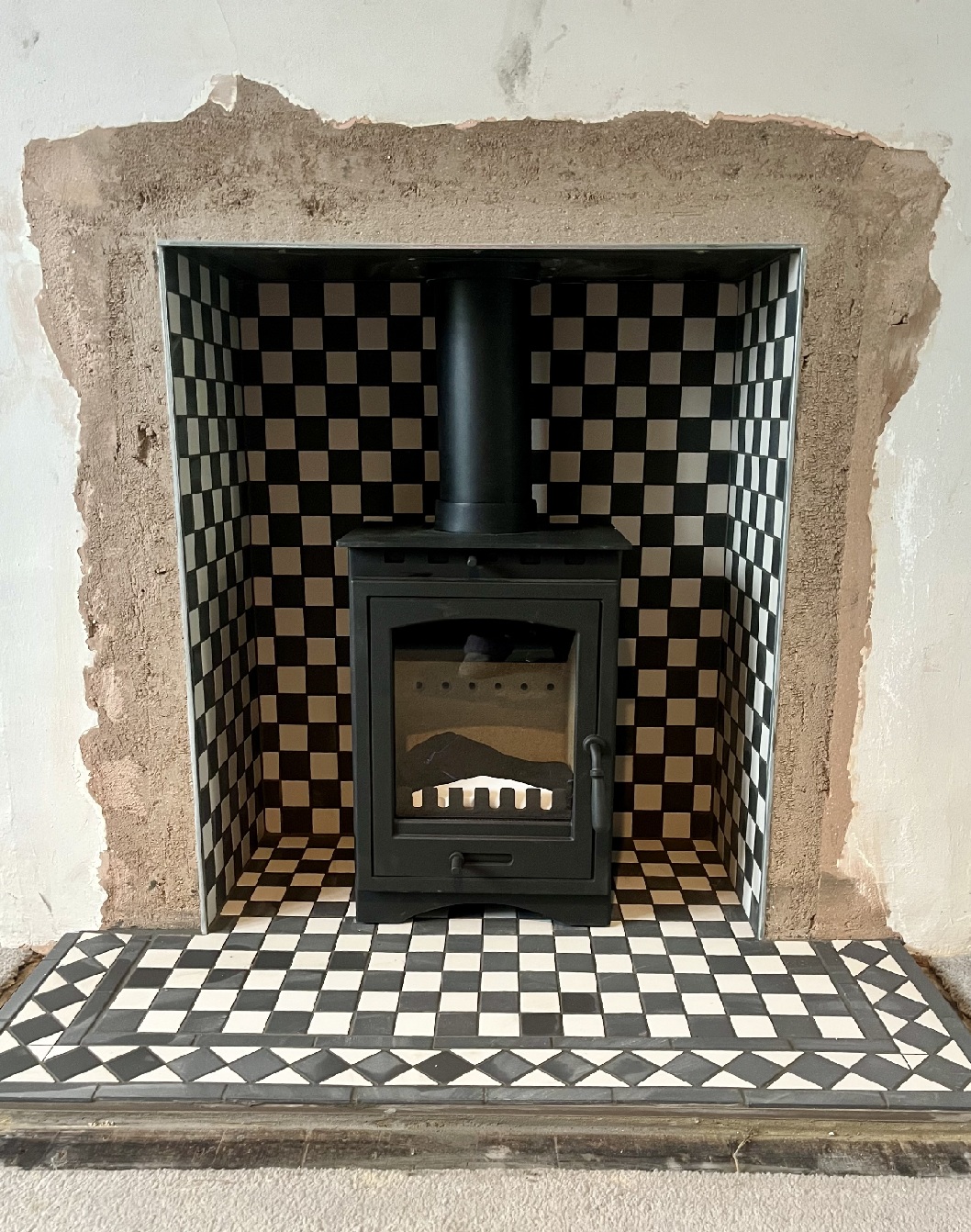 The final result &mdash; Victorian tiles and a sleek black stove creating a timeless focal point.